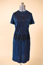 Load image into Gallery viewer, Vintage 1960s two piece midnight blue lurex set is shown from the front. This set has a short sleeve top with black velvet daisies. 
