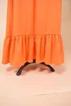 Load image into Gallery viewer, Vintage maxi length orange 70s poly gown is shown in close up. This maxi length dress has a bottom ruffle tier. 
