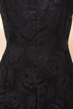 Load image into Gallery viewer, Vintage 1960s black swirl print jacquard silk dress is shown in close up. This dress is tailored at the waist. 

