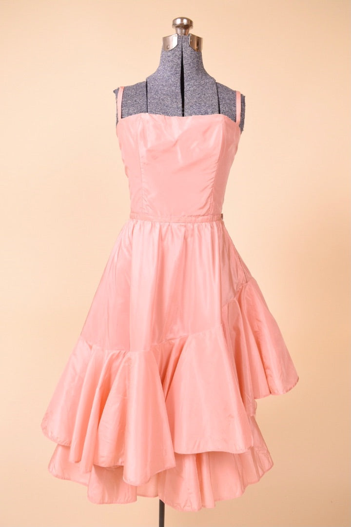 Vintage 1950's peach pink midi length ruffled skirt party dress is shown from the front. This dress has spaghetti straps.