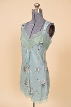 Load image into Gallery viewer, Vintage seafoam green lacy floral tank top is shown from the side. This lacy blue star print silk tank has a v cut neckline. 
