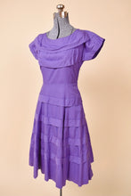 Load image into Gallery viewer, Vintage 50&#39;s midi length purple day dress is shown from the side. This dress has a boat neckline with cap sleeves. 
