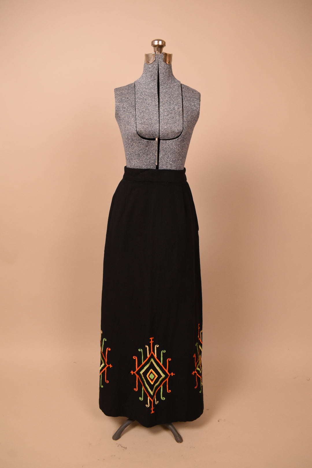 Vintage 60's black cotton maxi skirt is shown from the front. This skirt has boho colorful patterns embroidered at the bottom hem. 
