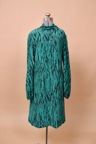 The dress faces forward on a mannequin. It has a mock neck and long sleeves.