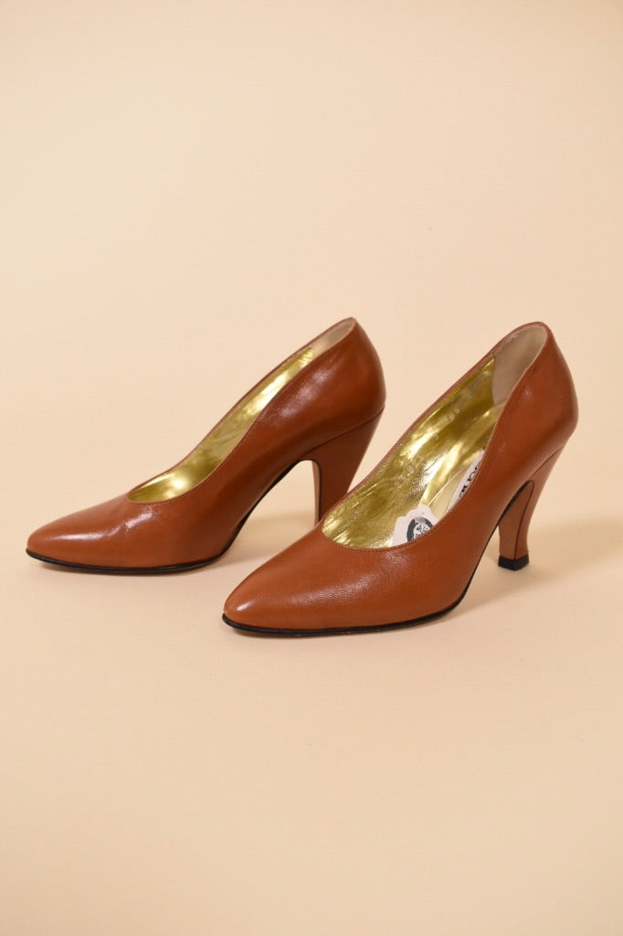 Vintage brown leather Escada heel pumps are shown from the side. These designer leather high heels have a gold interior. 