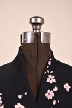 Load image into Gallery viewer, Vintage black and pink floral print dress is shown in close up. This dress has a raised collar with a v neckline. 
