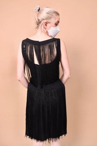 The back of the dress is seen modeled on a person. It has an open back with a long fringe.