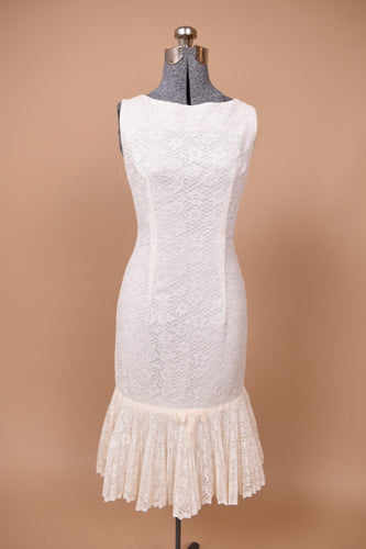 Vintage 1960s white lace mermaid dress is shown from the front. This dress has a drop waist with a pleated lace skirt.