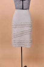 Load image into Gallery viewer, The skirt faces forward on the mannequin. The piece has three thick fringe stripes.
