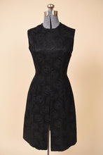 Load image into Gallery viewer, Vintage 1960&#39;s black silk jacquard tunic dress by Plymouth is shown from the front. This sleeveless rose print black dress has a high slit up the front of the skirt. 

