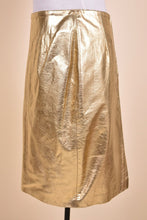 Load image into Gallery viewer, Vintage 90s shiny gold leather skirt by Kenar is shown from the side. 

