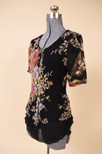Load image into Gallery viewer, Vintage 90s black floral print sheer floaty top is shown from the side. This top has a pink and purple flower print design. 
