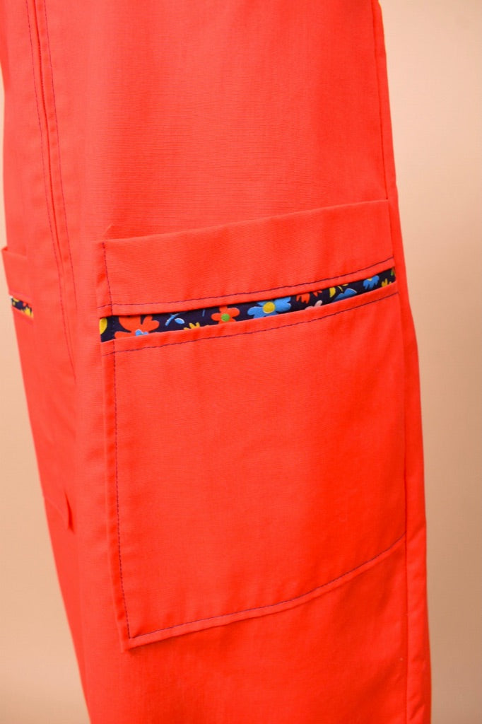 Vintage red zipper house dress shown in close up. This dress has blue floral lining in the front pocket.