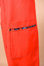 Load image into Gallery viewer, Vintage red zipper house dress shown in close up. This dress has blue floral lining in the front pocket.
