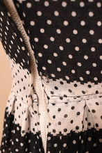 Load image into Gallery viewer, Vintage 50s black and white polka dot dress is shown in close up. This dress has a zipper on the side.
