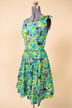 Load image into Gallery viewer, Vintage 60&#39;s blue and green flower print fit n flare day dress is shown from the side. This dress is tailored at the waist with a circle skirt. 
