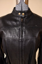 Load image into Gallery viewer, Vintage black leather jacket is shown in close up. This black leather moto jacket has two snaps at the collar. 
