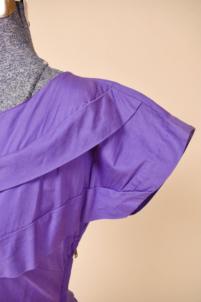 Vintage fifties purple cotton dress by Brief Measure is shown in close up. This dress has cap sleeves. 
