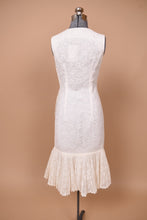 Load image into Gallery viewer, Vintage sixties white lace midi length dress is shown from the back. This dress has a mermaid silhouette with a pleated lace skirt.
