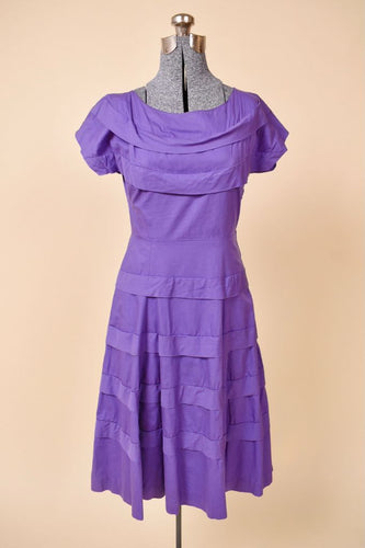 Vintage 1950's purple cotton dress is shown from the front. This dress has draped ruffles at the neckline and skirt. 
