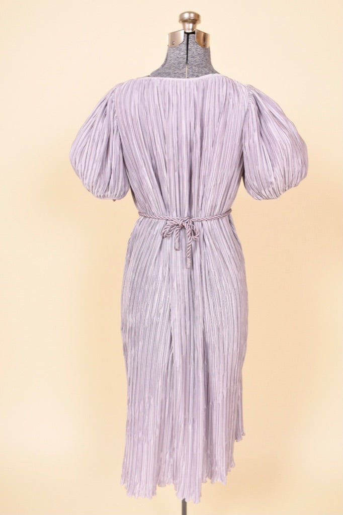 Vintage Pierre Labiche eighties pastel purple micropleat grecian dress is shown from the back. This purple midi length dress has puff sleeves. 