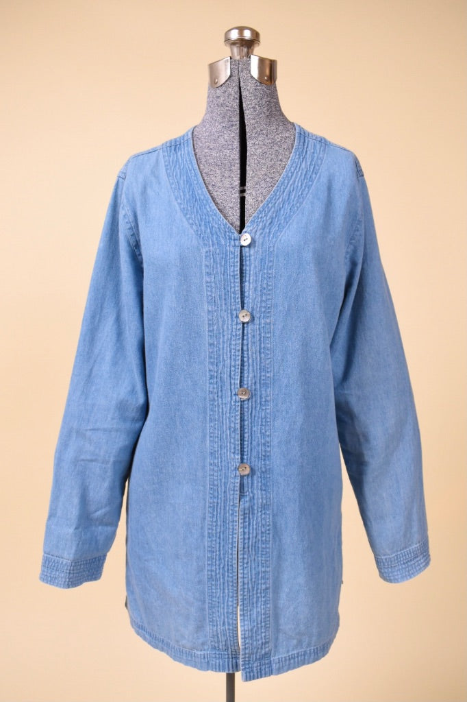 Vintage light wash blue denim button down top by Newport News is shown from the front. This blue top has a v neckline. 