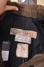 Load image into Gallery viewer, Vintage 60&#39;s olive green waxed canvas raincoat is shown in close up. This jacket has a tag that reads Dickson Constant Toiles for Le Clan J, made in France expressly for Joseph Horne Co. 
