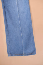 Load image into Gallery viewer, Vintage 1970s blue denim flare jeans are shown in close up. These flare jeans have brown contrast stitching. 
