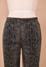 Load image into Gallery viewer, Vintage low rise cotton cigarette pants are shown in close up. These grey pants have a black snakeskin print.
