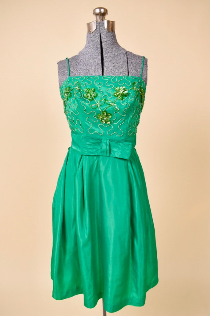 Vintage 1960's green acetate mini party dress is shown from the front. This dress has a straight neckline with emerald sequin flowers. 
