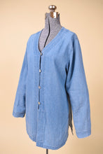 Load image into Gallery viewer, Vintage blue denim v neck button down top by Newport News is shown from the side. This top has iridescent shell buttons down the front. 
