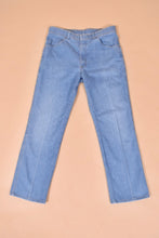 Load image into Gallery viewer, Vintage 1970&#39;s light wash blue denim jeans by Comfort Action Sports are shown from the front. These high waisted flare jeans have a pleat down the front. 
