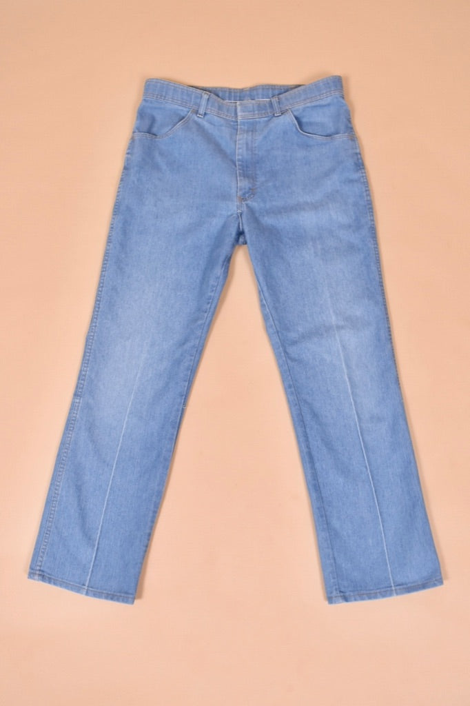 Vintage 1970's light wash blue denim jeans by Comfort Action Sports are shown from the front. These high waisted flare jeans have a pleat down the front. 