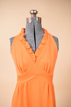 Load image into Gallery viewer, Vintage 1970s orange polyester ruffled maxi dress is shown in close up. This bright gown has a halter neckline.
