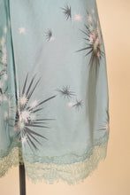 Load image into Gallery viewer, Vintage seafoam green mini slip by Harknam is shown in close up. This slip is a blue green color with white and grey star details. 
