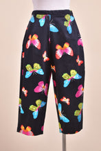 Load image into Gallery viewer, Vintage 2000&#39;s black stretch capri pants are shown from the back. These capri pants have green, blue, and pink butterflies. 
