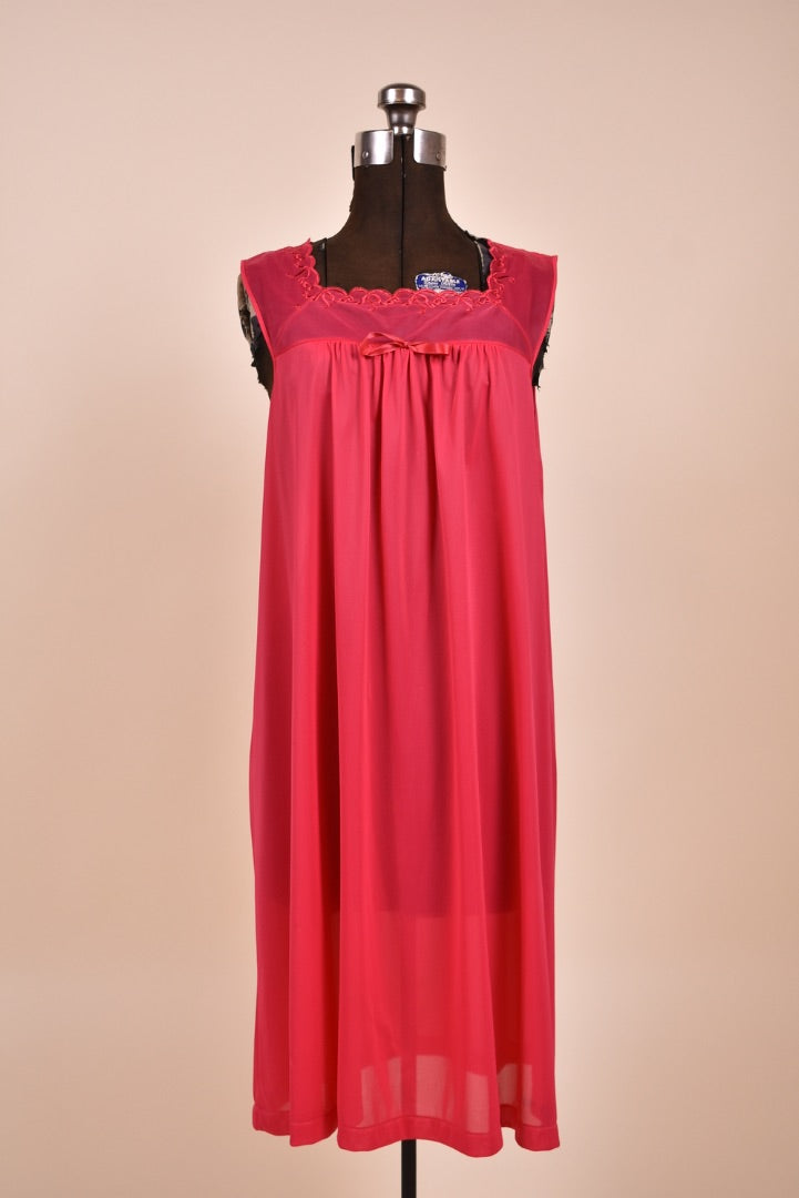 Vintage hot pink square neck midi length nightgown is shown in close up. This nightgown has a bow at the neckline. 