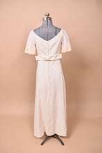 Load image into Gallery viewer, The dress faces backward on a mannequin. There are center clasps at the back and a wide narrow bow.
