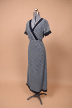 Load image into Gallery viewer, Vintage Laura Ashley navy blue calico floral print maxi dress is shown from the side. This dress has a navy lace trim at the bust and sleeves.
