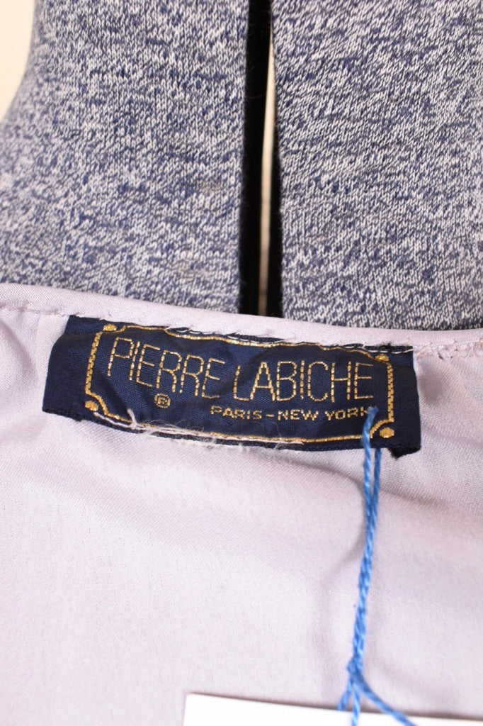 Vintage lilac purple midi length micropleat puff sleeve dress is shown in close up. This dress has a tag that reads Pierre Labiche Paris New York. 