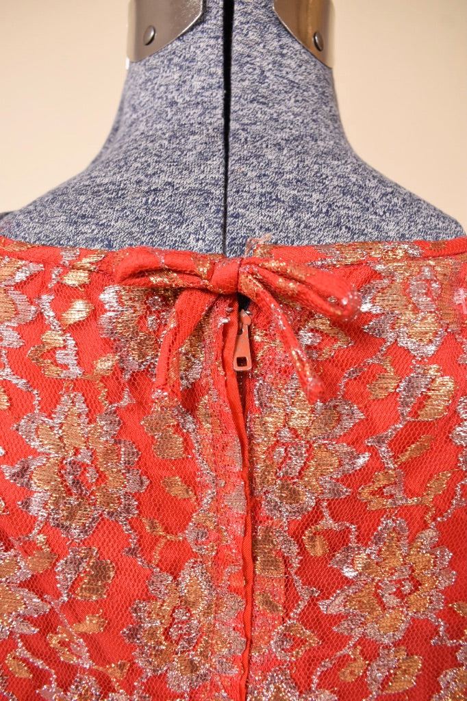 Vintage red 60's party mini dress is shown in close up. This dress has a gold and silver metallic lace overlay.