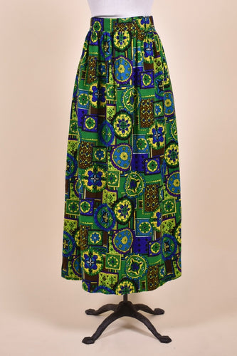 Vintage 1970's green and blue stain glass print maxi skirt by Dutchmaid is shown from the front. This skirt has a high waisted fit.