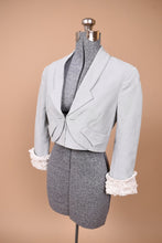 Load image into Gallery viewer, Vintage Zac Posen slate blue blazer is shown from the side. This blazer is cropped with a gathered white tulle detail at the cuffs of the sleeves.
