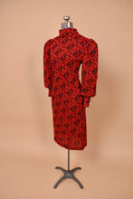 Load image into Gallery viewer, Vintage eighties bodycon red and black patterned knit midi length dress is shown from the side. This dress has dramatic puff sleeves.
