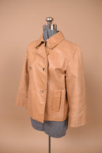 Load image into Gallery viewer, Vintage tan double breasted leather jacket is shown from the side. This jacket has a cropped fit.
