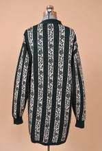 Load image into Gallery viewer, Vintage eighties forest green and white striped floral granny sweater is shown from the back. This sweater is long and could be worn slouchy and oversized. 
