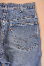 Load image into Gallery viewer, Vintage levis light wash seventies jeans are shown in close up. These jeans have an orange tab.
