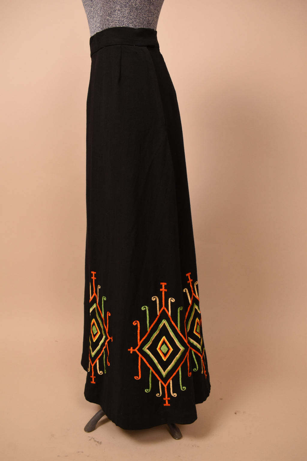 Vintage 60's black flared cotton maxi skirt is shown from the side. This skirt has an abstract diamond shape ribbon design at the bottom hem.