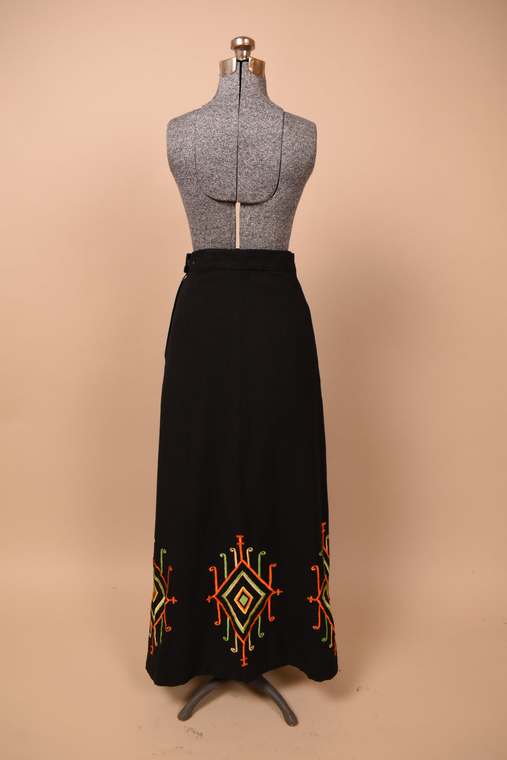 Vintage 60's black cotton a line maxi skirt is shown from the back. This skirt has an embroidered diamond motif at the bottom hem. 