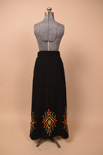 Load image into Gallery viewer, Vintage 60&#39;s black cotton a line maxi skirt is shown from the back. This skirt has an embroidered diamond motif at the bottom hem. 
